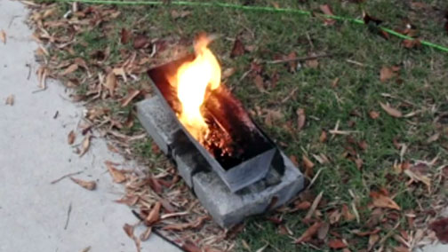 A golf ball sized lump of tar log burning. The tar log material burned when ignited.